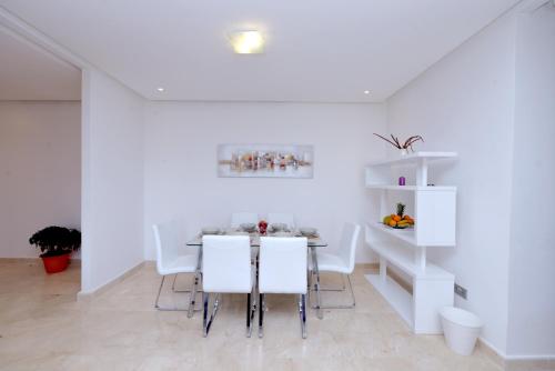 拉巴特Privat Apartments Prestigia Hay Riad的白色的用餐室配有桌子和白色的椅子