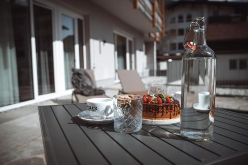 韦斯滕多夫Mountainview Apartments的桌子,桌子上放着一瓶,蛋糕和杯子