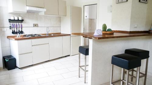 蒂沃利ApartHotel Le Sirene - CHALET的厨房配有白色橱柜和蓝色凳子