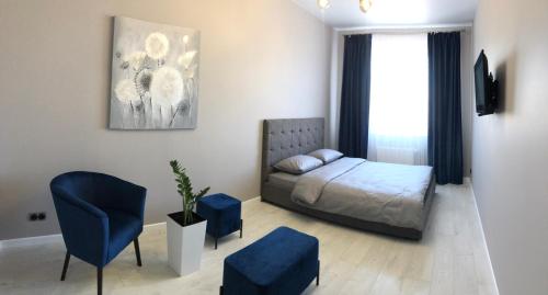 罗夫诺Люкс апартаменти в центрі Жк Театральний的一间卧室配有一张床和一张蓝色椅子