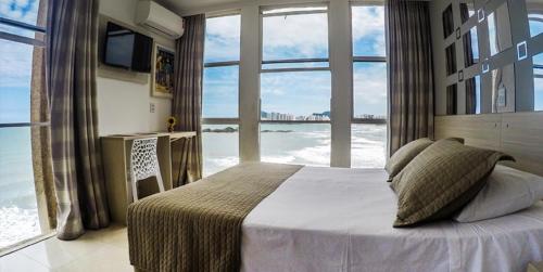 瓜鲁雅Grand Hotel Guarujá - A sua Melhor Experiência Beira Mar na Praia!的一间卧室设有一张床,享有海景