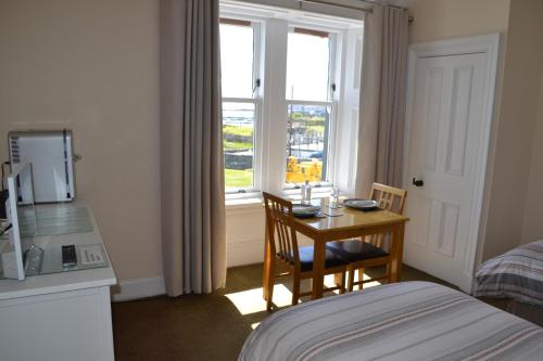 埃伦港Eilidh’s Guest House的客房设有桌子、床和窗户。