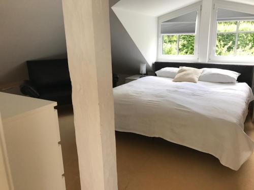 多瑙艾辛根Maisonette Ferienappartement mit Garten的卧室配有一张白色大床和两个窗户