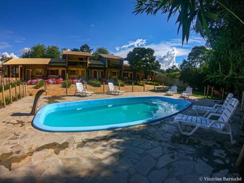 卡兰卡斯Pousada Vila Mandalah的一个带椅子的游泳池以及一座房子