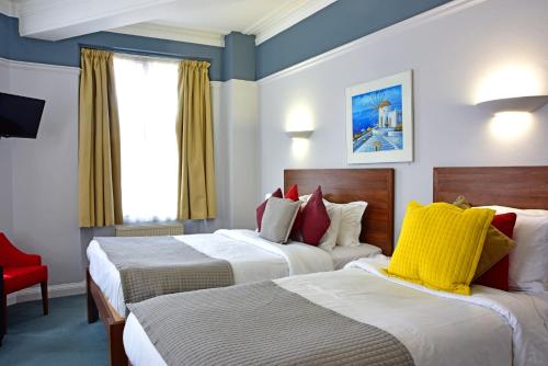 牛津皇家牛津酒店的酒店客房,设有两张床和一张红色椅子