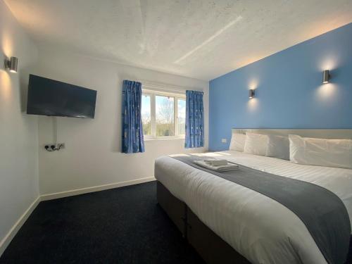 米尔顿凯恩斯National Badminton Centre Lodge & Health Club的一间卧室配有一张带蓝色墙壁的大床