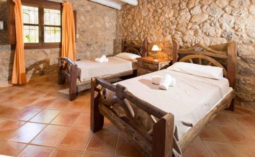 卡普德佩拉Sa Torre II的一间卧室设有两张床和石墙