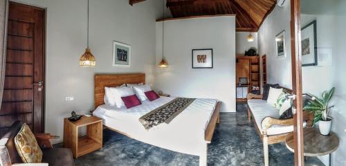 EkasOmbak Resort at Ekas , a luxury surf and kite surf destination的一间卧室配有一张大床和一把椅子