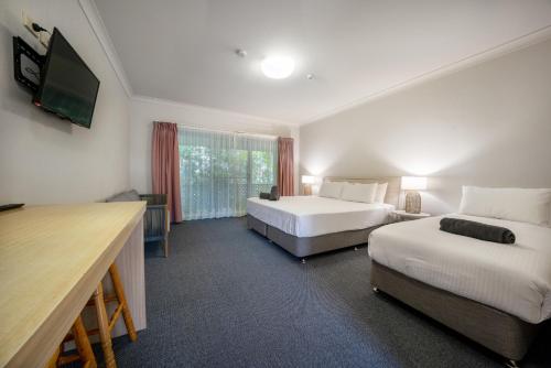 伍尔古尔加Woolgoolga Coast Motel的酒店客房设有两张床和一台平面电视。