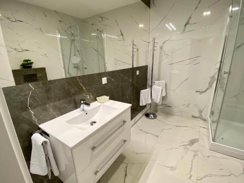米兹多洛杰Fischer Apartments的白色的浴室设有水槽和淋浴。