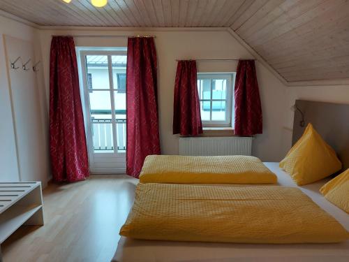 施特罗布尔K3 Ferienhaus的配有红色窗帘的客房内的两张床