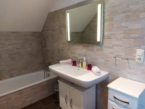 施特罗布尔K3 Ferienhaus的浴室配有盥洗盆、镜子和浴缸