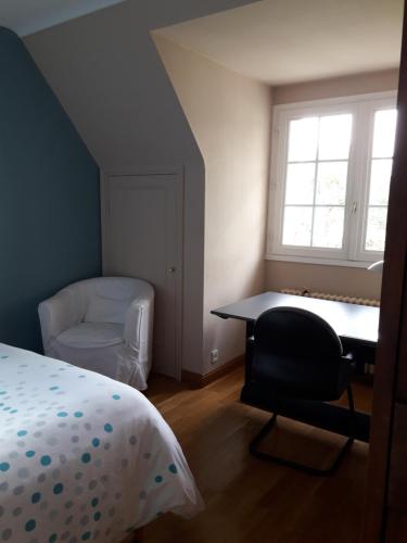 高伊斯瑙Chambre dans villa的一间卧室配有一张床、一张桌子和一把椅子