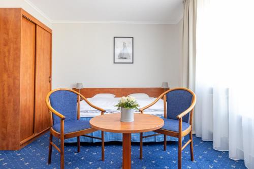米兹多洛杰马里纳酒店的配有桌子和两把椅子及一张床的房间