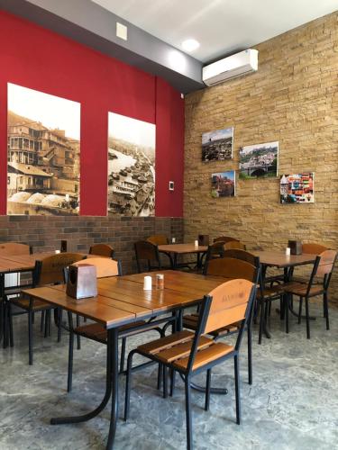 第比利斯Hotel Nabadi的餐厅设有木桌和椅子,拥有红色的墙壁