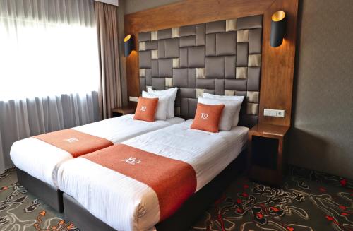 阿姆斯特丹XO酒店公园西店的酒店客房 - 带两张带橙色枕头的床