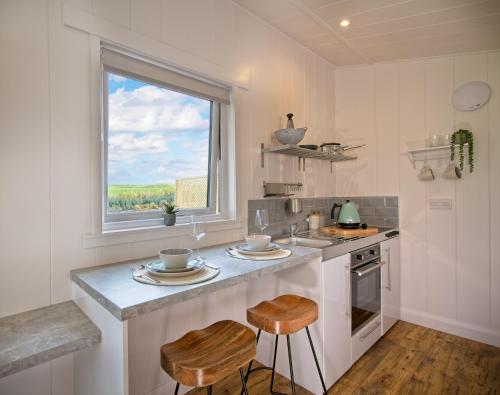 RingfordThe Pond Lodges Barstobrick的厨房配有带2张凳子的柜台和窗户。