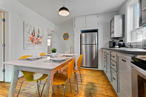 魁北克市Les Appartements du 790的厨房配有白色的桌子和黄色的椅子