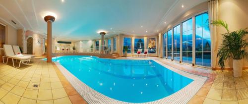 迈尔霍芬Alpenhotel Stefanie - direkt buchbar的大型游泳池,位于带大窗户的房屋内