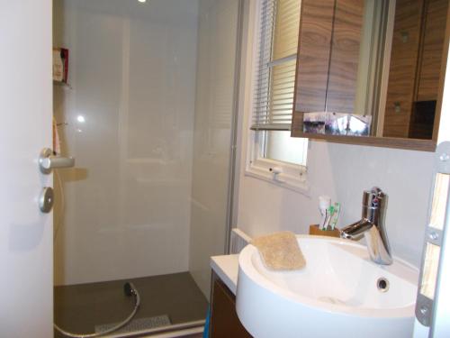 加斯泰mobilhome charme funpass et wifi inclus的白色的浴室设有水槽和淋浴。