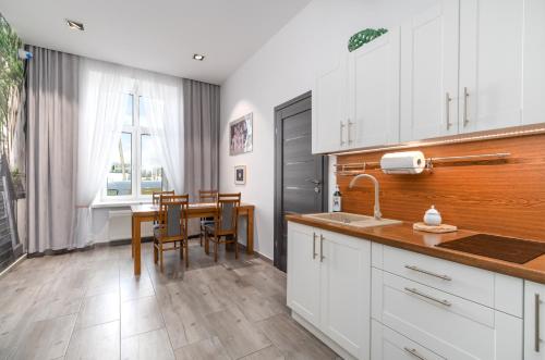 热舒夫Nasze Kamienice Apartament Express Rzeszów Główny的厨房配有白色橱柜和桌椅