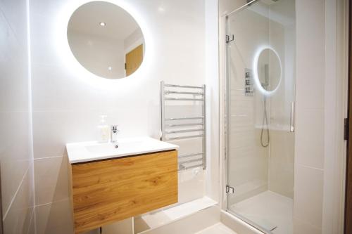 纽基Stunning Two Bed Sea View Apartment with Pool & Gym的浴室配有盥洗盆和带镜子的淋浴