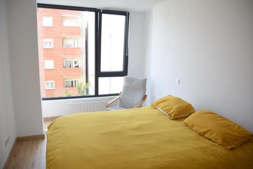 桑坦德VACARE - Apartamento 3 habitaciones, Capricho en el centro de Santander!的一间卧室配有一张黄色的床、椅子和窗户