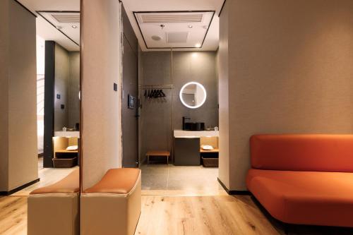 无锡zmaxhotels 无锡新加坡工业园机场店的走廊上设有橙色沙发和镜子