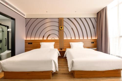 无锡zmaxhotels 无锡新加坡工业园机场店的配有白色床单的酒店客房内的两张床
