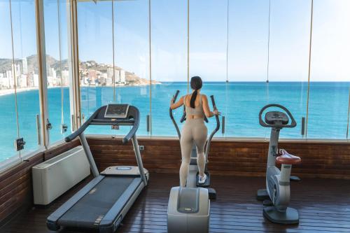 贝尼多姆威尼斯精品别墅酒店的一位在健身房的跑步机上看海洋的女人