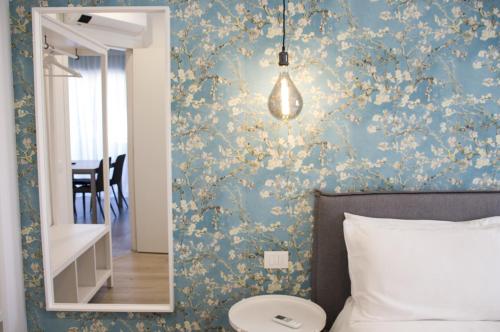特伦托Bloom Apartments的一间卧室设有蓝色墙壁、花卉图案的壁纸和镜子