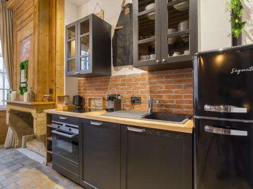 里昂HOST INN - CŒUR VIEUX LYON & SPA的一间厨房,配有黑色家电和砖墙