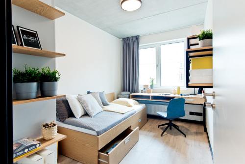 格但斯克MILESTONE Gdańsk Center的小房间设有一张床、一张桌子和一张书桌