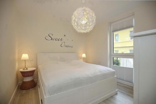 博尔滕哈根Strandvilla Scholle - Dorsch Wohnung 02的卧室配有白色的床和吊灯。