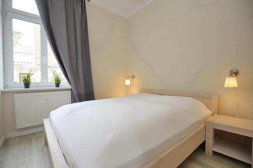 博尔滕哈根Villa Triton Wohnung 01的窗户客房内的一张白色床