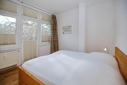 博尔滕哈根Villa Triton Wohnung 03的白色卧室设有一张大床和两个窗户