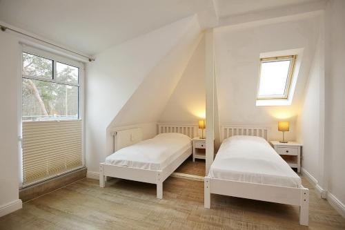 博尔滕哈根Villa Triton Wohnung 05的白色客房的两张床,设有窗户