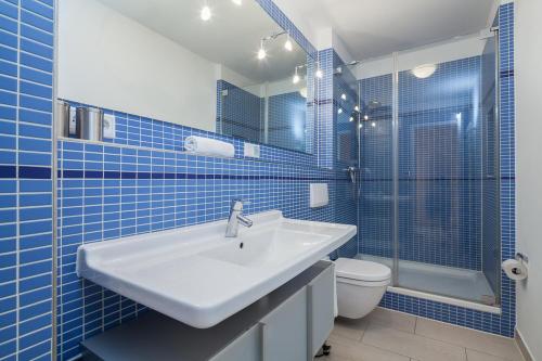 博尔滕哈根Dünenblick Wohnung 17的蓝色瓷砖浴室设有水槽和卫生间