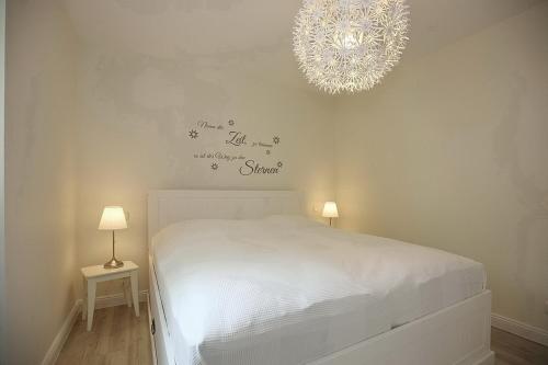 博尔滕哈根Strandvilla Scholle - Lachs Wohnung 01的卧室配有白色的床和吊灯。