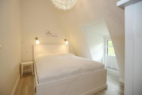 博尔滕哈根Strandvilla Scholle - Scholle Wohnung 05的配有吊灯的客房内的白色床