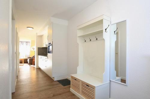 博尔滕哈根Papillon Wohnung 16-7的厨房设有白色的墙壁和白色的衣柜。
