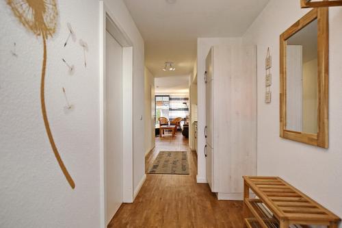 博尔滕哈根Papillon Wohnung 04-1的一间拥有白色墙壁和木地板的走廊