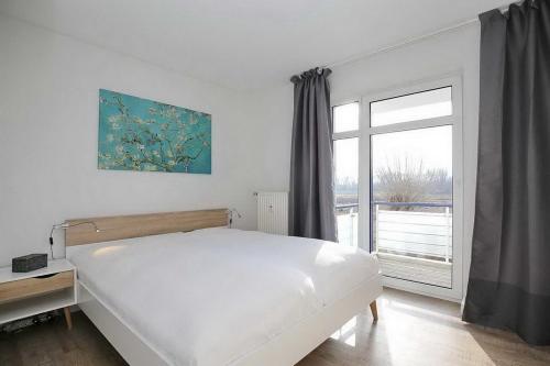 博尔滕哈根Haffblick Wohnung 42的白色的卧室设有床和窗户
