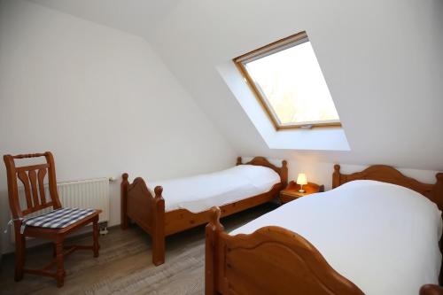 博尔滕哈根Papillon Wohnung 01-6的客房设有两张床、一个窗户和椅子。