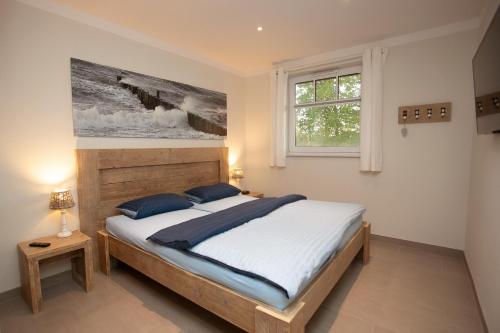 博尔滕哈根Reethaus Am Mariannenweg 11a的卧室配有一张床,墙上挂有绘画作品