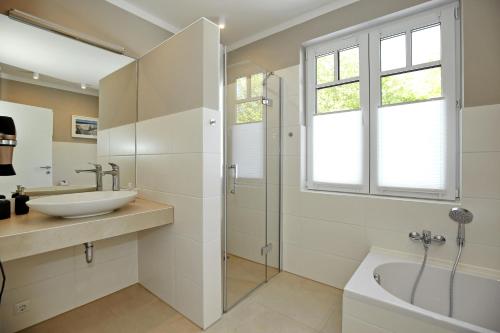 维滕贝克Haus am Wald Wohnung Meer的浴室配有水槽、淋浴和浴缸。