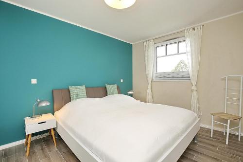 博尔滕哈根Reethaus Am Mariannenweg 20b的卧室配有白色的床和蓝色的墙壁