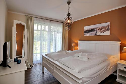 海利根达姆Linden-Palais Wohnung 03的卧室配有一张白色大床和电视。