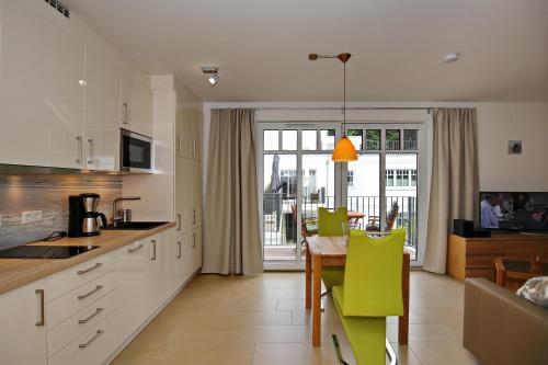 海利根达姆Linden-Palais Wohnung 27的厨房配有桌子和绿色椅子