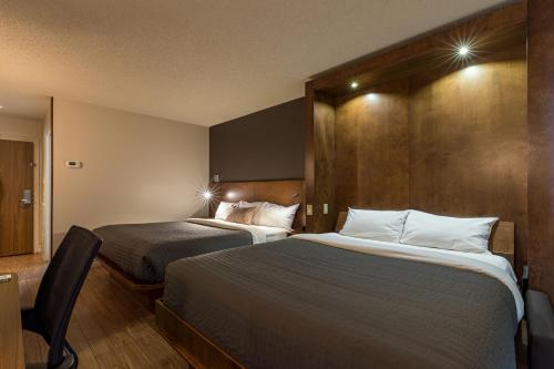 魁北克市魁北克N酒店的酒店客房,配有两张床和椅子